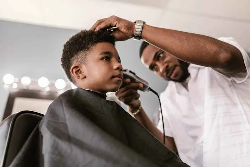 prix coupe cheveux santo antao, un homme fait un dégradé à un enfant.