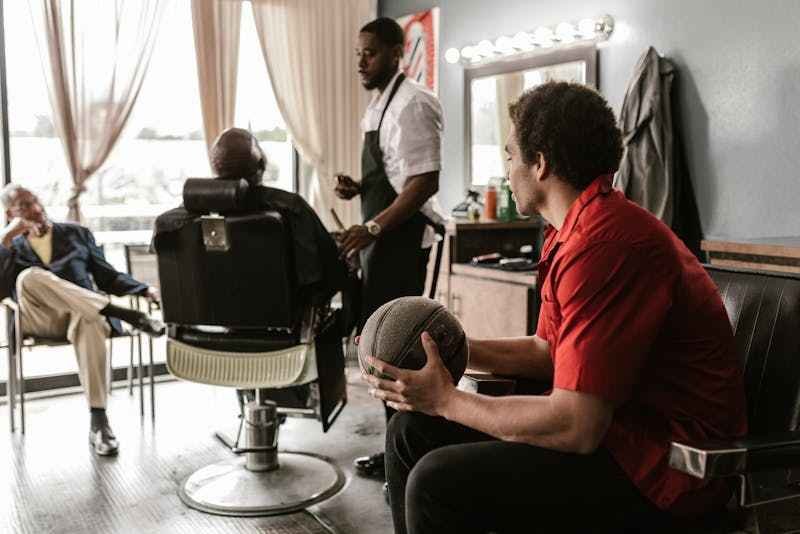salon-coiffure-santo-antao,un homme se fait coiffer par un homme, les autres attendent autour salon coiffure santo antao